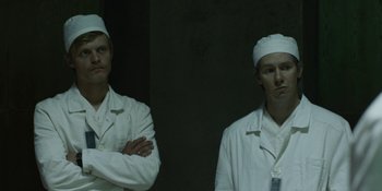 Movie still from “Chernobyl” (2019), directed by Johan Renck – Two men in white lab coats standing next to each other; Medium shot, Low angle