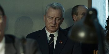 Movie still from “Chernobyl” (2019), directed by Johan Renck – An older man wearing a suit and tie; Close Up shot, Over the shoulder angle
