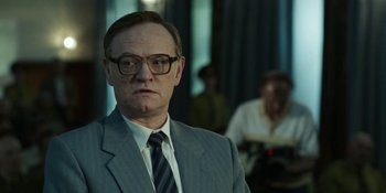 Movie still from “Chernobyl” (2019), directed by Johan Renck – A man wearing a suit and tie in a room; Close Up shot, Over the shoulder angle