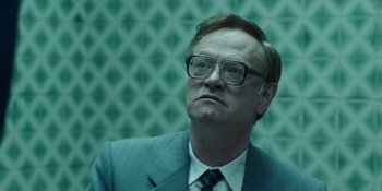 Movie still from “Chernobyl” (2019), directed by Johan Renck – A man in a suit and glasses looking up; Close Up shot, Low angle