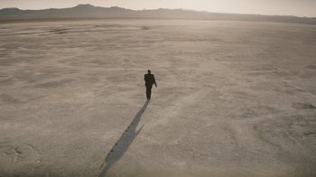 Movie still from “True Detective” (2014), created by Issa López – A man in a suit is walking across the desert; Extreme Wide shot, High angle