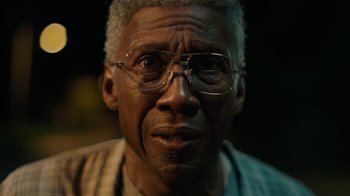 Movie still from “True Detective” (2014), created by Issa López – An older man wearing glasses and looking at the camera; Close Up shot, Low angle