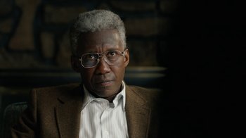 Movie still from “True Detective” (2014), created by Issa López – An older man wearing glasses and a jacket; Close Up shot, Over the shoulder angle