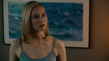 Movie still from “True Detective” (2014), created by Issa López – A beautiful blonde woman standing in front of a painting; Close Up shot, Over the shoulder angle