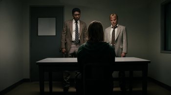 Movie still from “True Detective” (2014), created by Issa López – Two men and a woman standing in front of a table; Medium shot, Over the shoulder angle