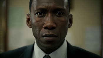Movie still from “True Detective” (2014), created by Issa López – A person wearing a suit and tie; Close Up shot, Low angle