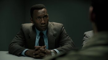 Movie still from “True Detective” (2014), created by Issa López – A man sitting at a table with his hands crossed; Close Up shot, Over the shoulder angle