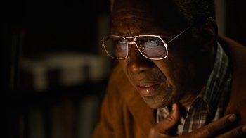 Movie still from “True Detective” (2014), created by Issa López – An older man wearing glasses looking at the camera; Close Up shot, High angle