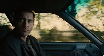 Movie still from “Children of Men” (2006), directed by Alfonso Cuarón – A man sitting in the passenger seat of a car; Close Up shot, Low angle