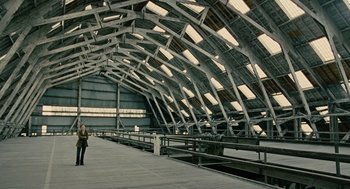 Movie still from “Children of Men” (2006), directed by Alfonso Cuarón – A person standing in a train station under a roof; Extreme Wide shot, High angle