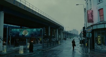 Movie still from “Children of Men” (2006), directed by Alfonso Cuarón – A person walking down a wet street in the rain; Extreme Wide shot, Low angle