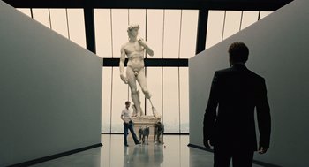 Movie still from “Children of Men” (2006), directed by Alfonso Cuarón – A man standing in front of a statue in a museum; Wide shot, Low angle