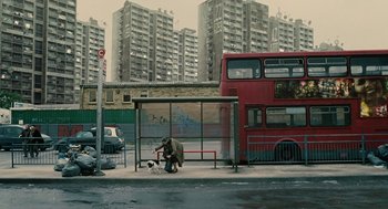 Movie still from “Children of Men” (2006), directed by Alfonso Cuarón – A man kneeling down at a bus stop with a dog; Extreme Wide shot, Low angle