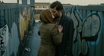Movie still from “Children of Men” (2006), directed by Alfonso Cuarón – A man and a woman are kissing in the street; Medium shot, Over the shoulder angle