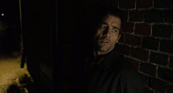 Movie still from “Children of Men” (2006), directed by Alfonso Cuarón – A person in a dark room; Close Up shot, Over the shoulder angle