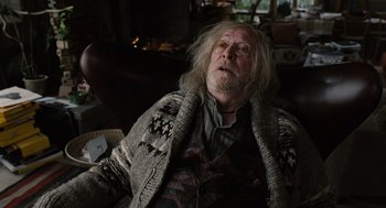 Movie still from “Children of Men” (2006), directed by Alfonso Cuarón – An old man with a long white beard sitting in a chair; Medium shot, Low angle