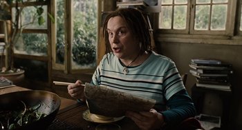 Movie still from “Children of Men” (2006), directed by Alfonso Cuarón – A woman sitting at a table with a plate in front of her; Medium shot, High angle