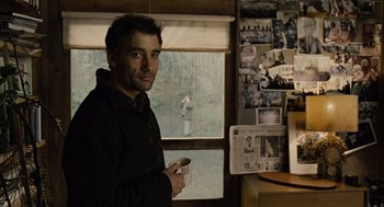 Movie still from “Children of Men” (2006), directed by Alfonso Cuarón – A man holding a coffee cup in front of a window; Medium shot, Over the shoulder angle