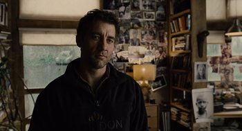 Movie still from “Children of Men” (2006), directed by Alfonso Cuarón – A man standing in front of a wall covered in photos; Close Up shot, Over the shoulder angle