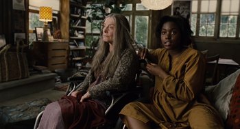 Movie still from “Children of Men” (2006), directed by Alfonso Cuarón – Two women sitting in a chair in a living room; Medium shot, Over the shoulder angle
