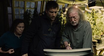 Movie still from “Children of Men” (2006), directed by Alfonso Cuarón – Two men looking at something on a table; Medium shot, Over the shoulder angle