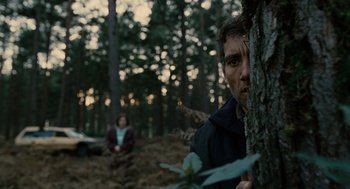 Movie still from “Children of Men” (2006), directed by Alfonso Cuarón – A man standing next to a tree in the woods; Medium shot, Low angle
