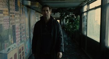 Movie still from “Children of Men” (2006), directed by Alfonso Cuarón – A man standing in an abandoned building with a gun; Medium shot, Low angle