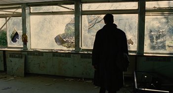 Movie still from “Children of Men” (2006), directed by Alfonso Cuarón – A man standing in front of a window looking outside; Wide shot, Low angle