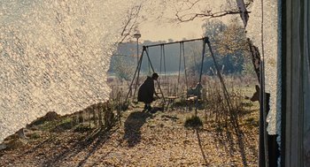 Movie still from “Children of Men” (2006), directed by Alfonso Cuarón – Two children play on a swing set in a park; Extreme Wide shot, High angle