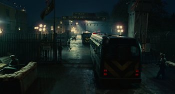 Movie still from “Children of Men” (2006), directed by Alfonso Cuarón – A train station at night with buses and people walking; Extreme Wide shot, High angle