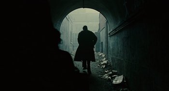 Movie still from “Children of Men” (2006), directed by Alfonso Cuarón – A person walking in a tunnel with a lot of trash around it; Wide shot, Low angle