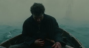 Movie still from “Children of Men” (2006), directed by Alfonso Cuarón – A man sitting in a boat on a body of water; Medium shot, High angle