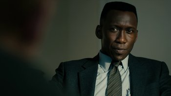 Movie still from “True Detective” (2014), created by Issa López – A man in a suit and tie looking at the camera; Close Up shot, Over the shoulder angle