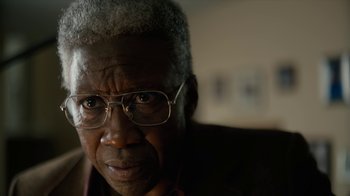 Movie still from “True Detective” (2014), created by Issa López – An older man wearing glasses looking at the camera; Close Up shot, Low angle
