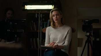 Movie still from “True Detective” (2014), created by Issa López – A woman sitting in a chair writing on a piece of paper; Medium shot, Over the shoulder angle