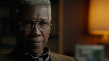 Movie still from “True Detective” (2014), created by Issa López – An older man wearing glasses looking at the camera; Close Up shot, Over the shoulder angle