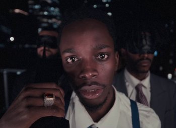 Movie still from “Sam Akpro - Death By Entertainment” (2023), directed by Pedro Takahashi – Close Up shot, Low angle
