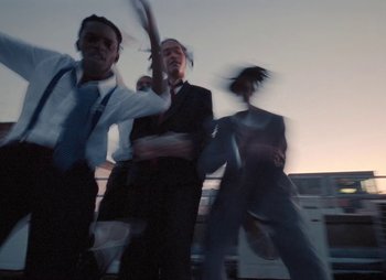 Movie still from “Sam Akpro - Death By Entertainment” (2023), directed by Pedro Takahashi – Medium shot, Low angle