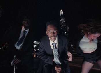 Movie still from “Sam Akpro - Death By Entertainment” (2023), directed by Pedro Takahashi – Medium shot, Low angle
