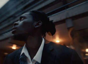 Movie still from “Sam Akpro - Death By Entertainment” (2023), directed by Pedro Takahashi – Close Up shot, Low angle