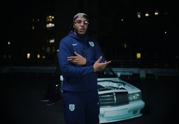 Movie still from “AJ Tracey - Bubble Bath” (2024), directed by Late Milk – Medium shot, Low angle