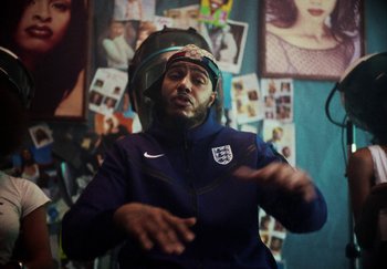 Movie still from “AJ Tracey - Bubble Bath” (2024), directed by Late Milk – Medium shot, Over the shoulder angle