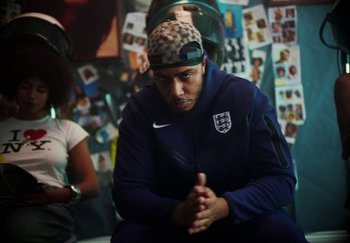 Movie still from “AJ Tracey - Bubble Bath” (2024), directed by Late Milk – Medium shot, Low angle