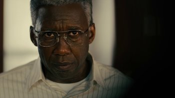 Movie still from “True Detective” (2014), created by Issa López – An older man wearing glasses looking at the camera; Close Up shot, Over the shoulder angle