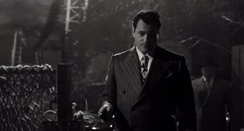 Movie still from “Trumbo” (2015), directed by Jay Roach – A black and white photo of a man in a suit and tie; Medium shot, Low angle