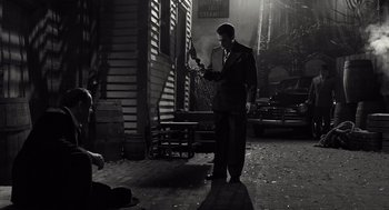 Movie still from “Trumbo” (2015), directed by Jay Roach – A black and white photo of a man standing in the dark; Wide shot, High angle