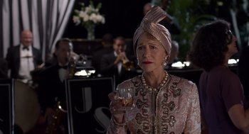 Movie still from “Trumbo” (2015), directed by Jay Roach – An older woman holding a wine glass in her right hand; Close Up shot, Over the shoulder angle