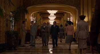 Movie still from “Trumbo” (2015), directed by Jay Roach – A group of men and women walking down a hall way; Wide shot, High angle