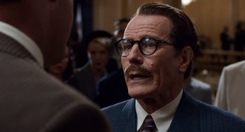 Movie still from “Trumbo” (2015), directed by Jay Roach – An older man with a mustache wearing glasses; Close Up shot, Over the shoulder angle