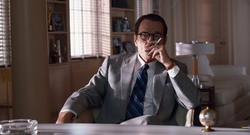 Movie still from “Trumbo” (2015), directed by Jay Roach – A man sitting at a table talking on a cell phone; Medium shot, Low angle
